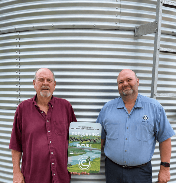 father and son holding farm sign